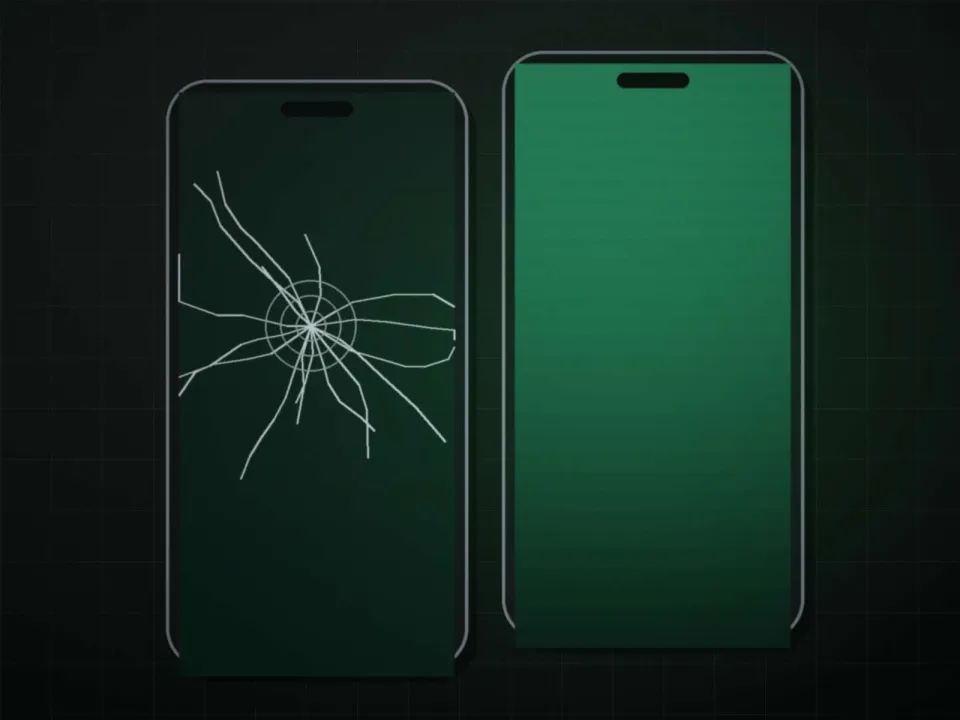 Écran de smartphone fissuré posé à côté d'un écran neuf, sur l'établi