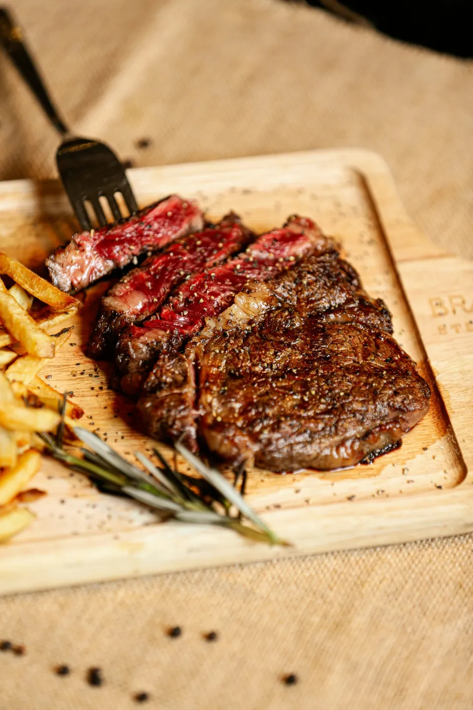 Côte de bœuf maturée tranchée sur une planche, frites maison