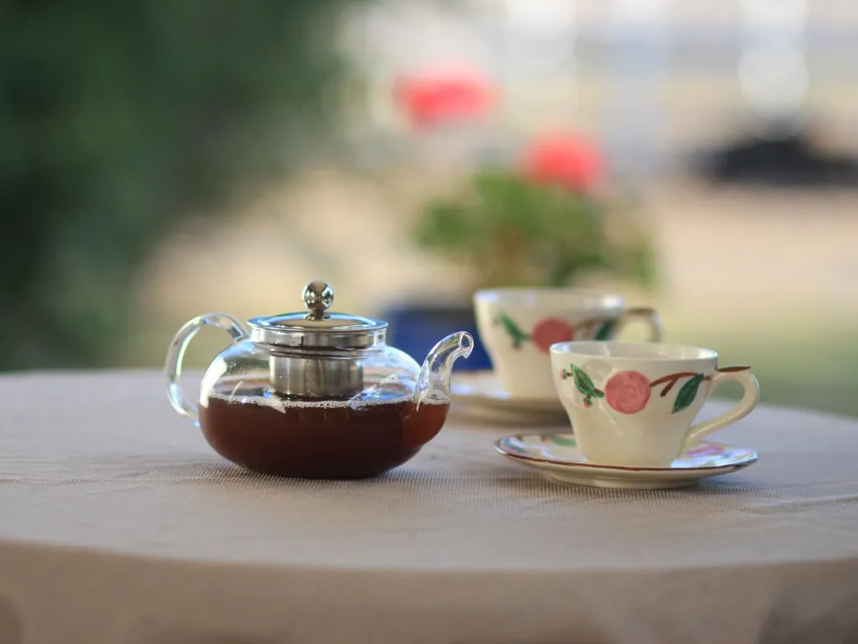 Tasse de thé et théière en verre sur une table claire