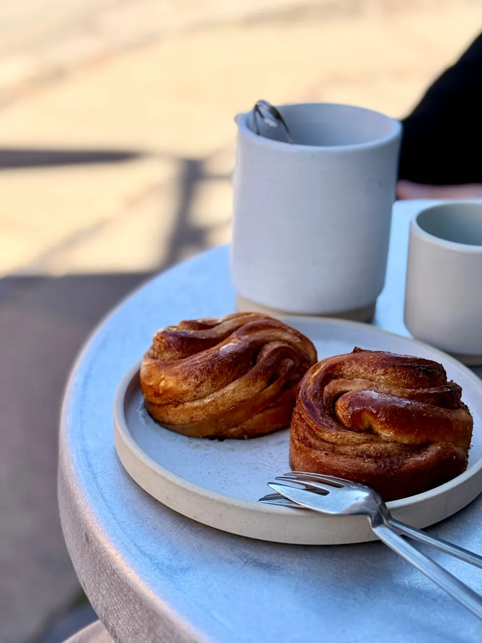 Viennoiserie dorée sur une assiette, à côté d'un café