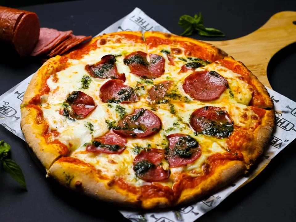 Pizza diavola au salami piquant sur une planche en bois