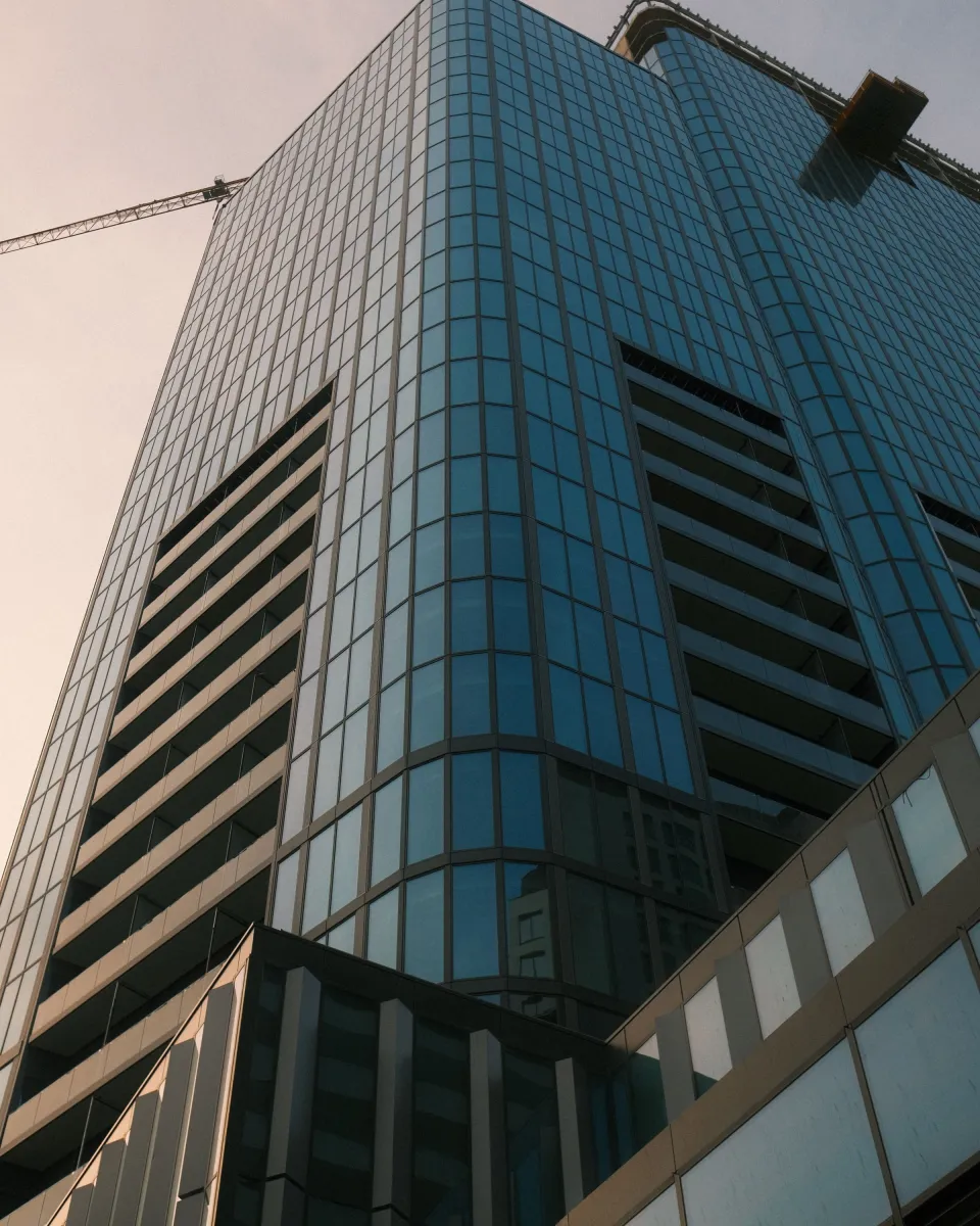 Façade vitrée d’un immeuble de bureaux, une silhouette au pied