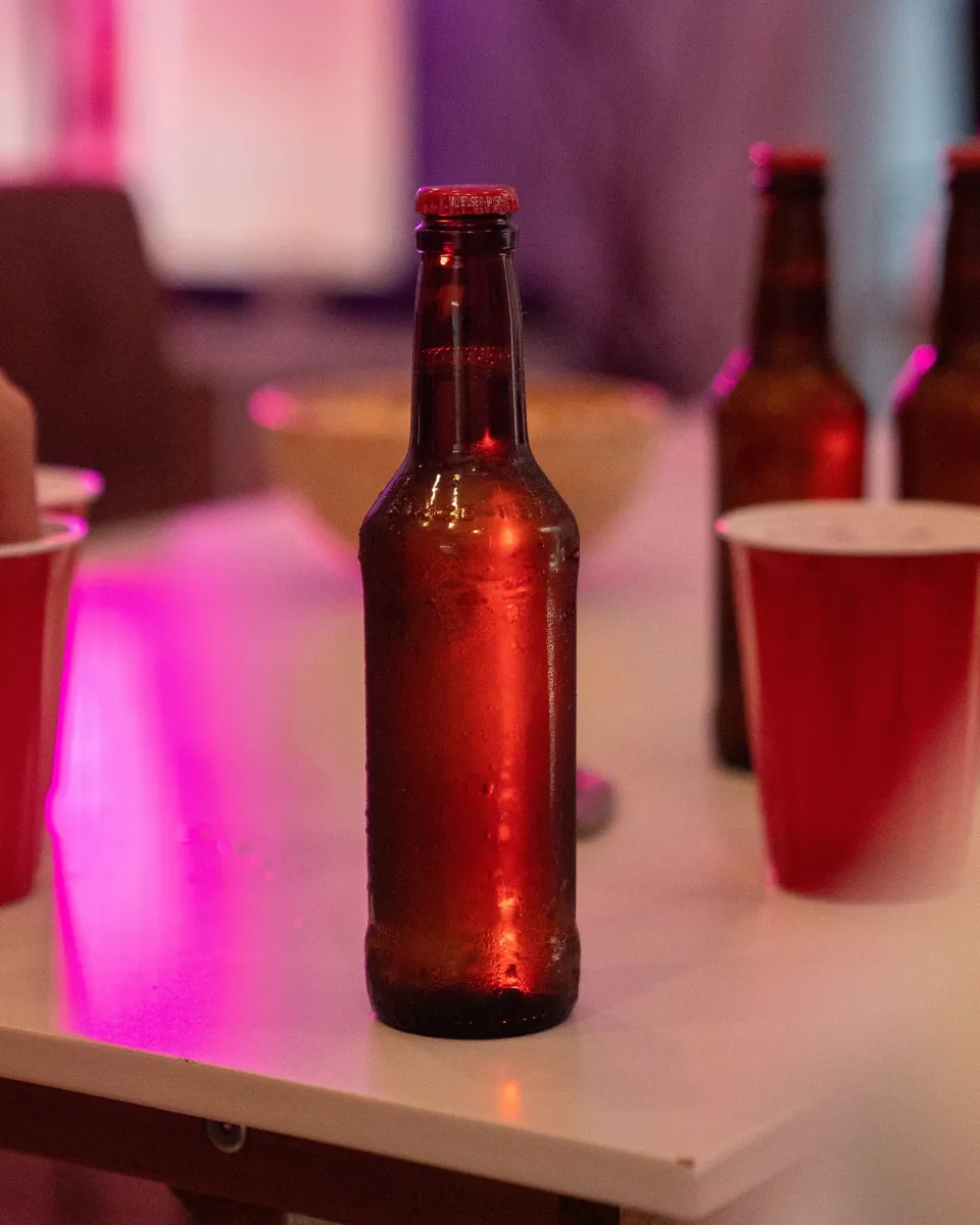 Bouteille bordeaux sur fond rosé, lumière latérale
